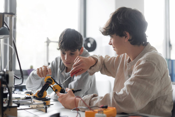 Young students using a 3D printer in the lab at school, one is using a screwdriver - Foto, Imagem