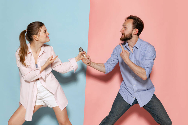 Relationship psychology. Couple of young funny and happy man and woman having fun isolated over blue and pink background. Human emotions, youth, love and active lifestyle concept - Photo, Image