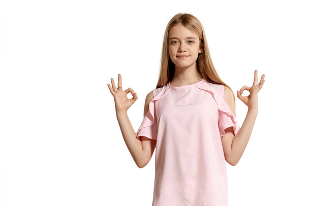 Studio portrait of a beautiful blonde adolescent in a pink t-shirt isolated on white background in various poses. She expresses different emotions posing right in front of the camera, smiling and - Foto, afbeelding