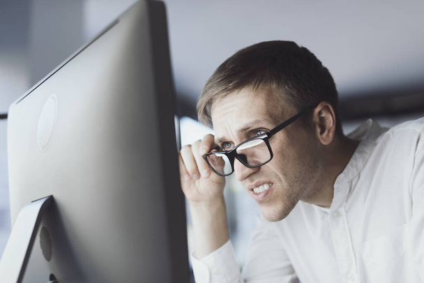Office worker with eyesight problem, he is trying to focus on the computer screen - Foto, Bild