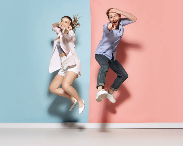 Silly mood. Couple of young funny and happy man and woman having fun isolated over blue and pink background. Human emotions, youth, love and active lifestyle concept - Photo, image