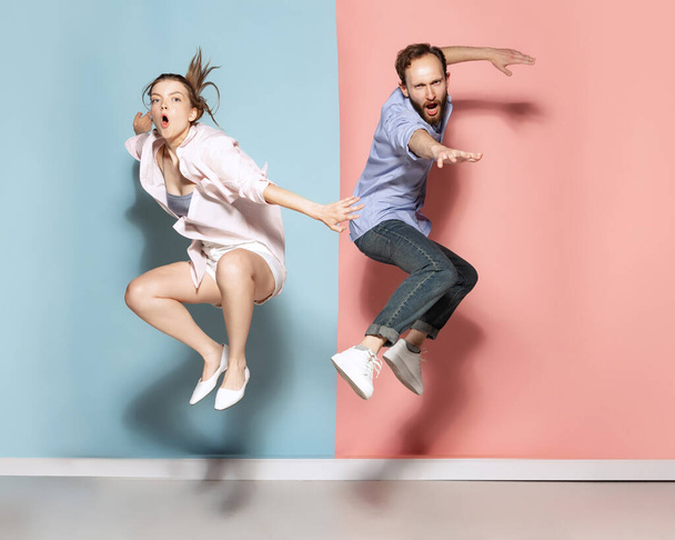 Silly mood. Couple of young funny and happy man and woman having fun isolated over blue and pink background. Human emotions, youth, love and active lifestyle concept - Photo, image
