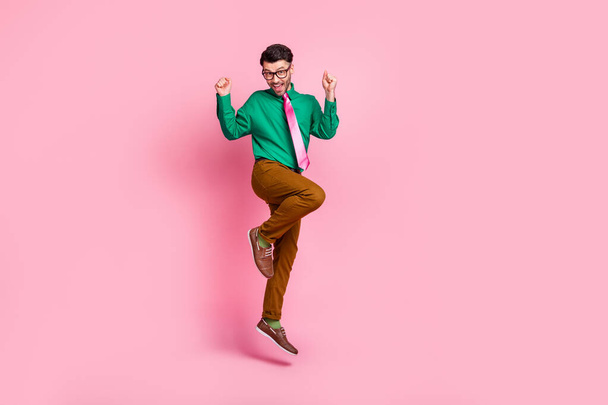 Full length photo of lucky pretty man dressed green shirt eyewear jumping rising fists isolated pink color background. - Foto, afbeelding