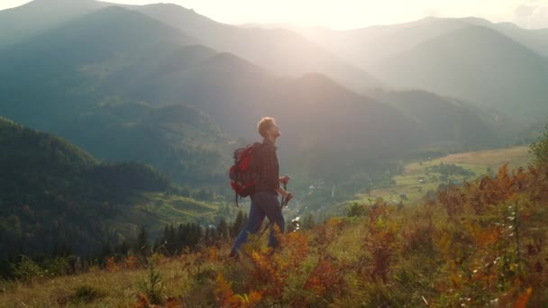 Active man walk mountains landscape. Sporty tourist hiking using trekking poles in morning sunrise. Backpacking hipster enjoy wanderlust travel lifestyle. Summer holiday activity recreation concept. - 映像、動画