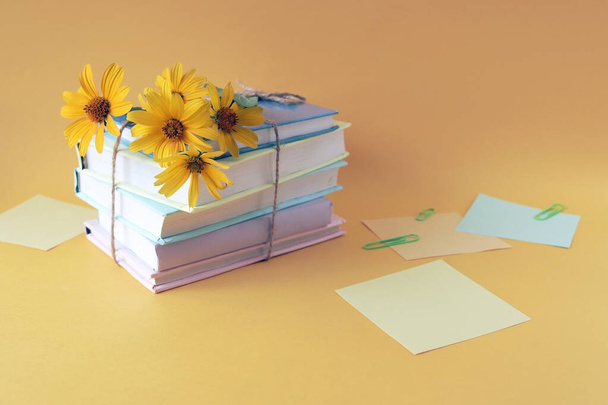 A stack of books with bookmarks from fresh chamomile flowers, on the background of note paper in pastel colors, the concept of education, back to school, reading, library, congratulation, postcard - Foto, immagini