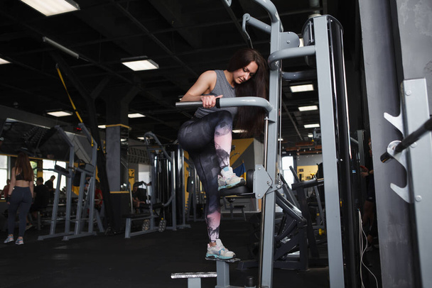Full length shot of a sportswoman doing stepping buttocks exercise in a gym machine, copy space - Foto, afbeelding
