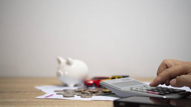 concept of money and finance to calculate income and expenses. Piggy Bank and  Pile of coins on graph paper on the table. Save money to buy a car. - 写真・画像