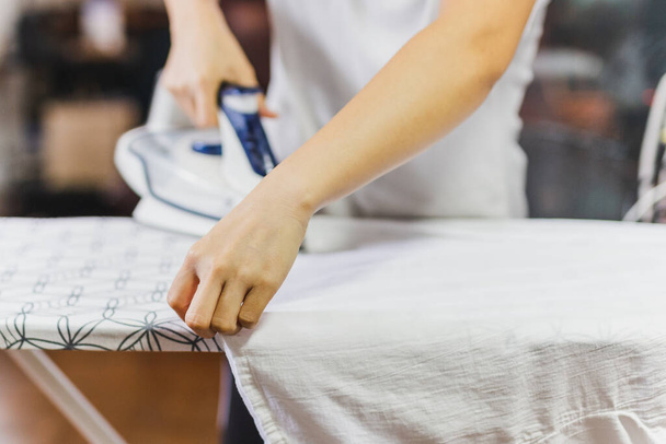 Housewife ironing clothes on an ironing board - Φωτογραφία, εικόνα