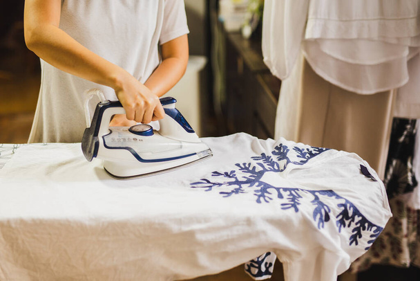 Caucasian housewife ironing on ironing board after laundry - Valokuva, kuva