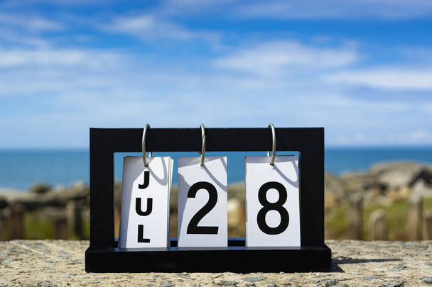 Jul 28 calendar date text on wooden frame with blurred background of ocean. Calendar date concept. - Фото, изображение