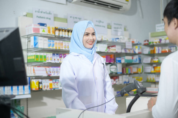 A Female muslim pharmacist counseling customer about drugs usage in a modern pharmacy drugstore. - 写真・画像