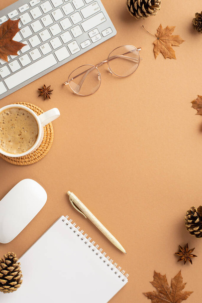 Autumn business concept. Top view vertical photo of keyboard computer mouse glasses cup of coffee rattan placemat fallen maple leaves anise pine cones reminder and pen on isolated beige background - Fotó, kép