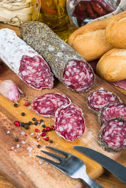 hele en gesneden salami met specerijen en kruiden - Foto, afbeelding