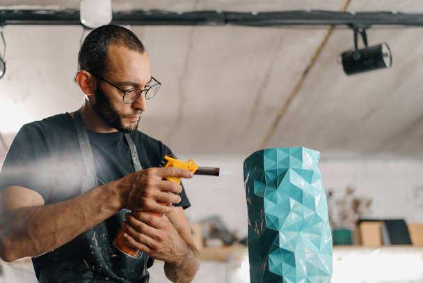 Artisan sculptor artist mixes using gas burner for burning paint and polymer - Фото, зображення