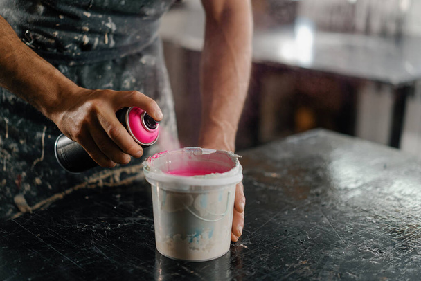 Artisan artist mixing paint in his workshop. Pink paint, paint mixer - 写真・画像