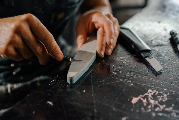 Close-up: artisan sculptor artist sharpening blade on a sharpener in a workshop - Fotoğraf, Görsel