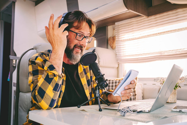 One hipster man travel and work on a camper van recording voice content for a podcast. Concept of online job and smart working or digital nomad free lifestyle. Male using laptop and microphone - Foto, Bild
