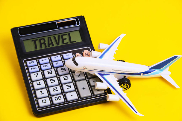 Calculator with inscription travel and white plane yellow background.Concept preparing budget for vacation - 写真・画像
