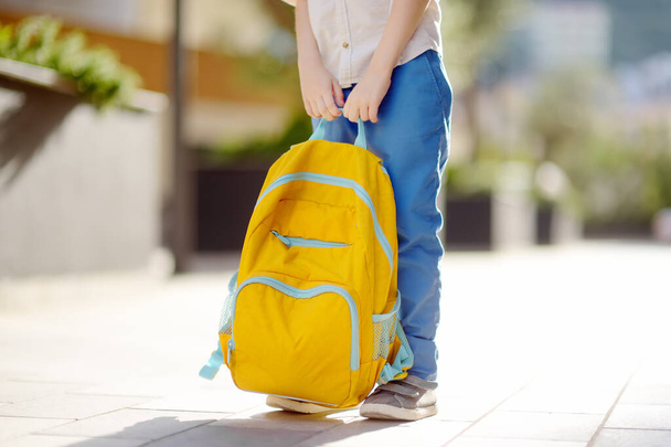 Little student with a backpack near school building. Close-up of child legs, hands and schoolbag of boy standing on staircase of schoolhouse. Kids back to school concept. - Photo, Image