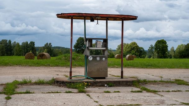 A very old fuel pump in an abandoned station. The old flow measurement used at the pump at the filling station. On the background of a beautiful mowed meadow - Foto, Bild