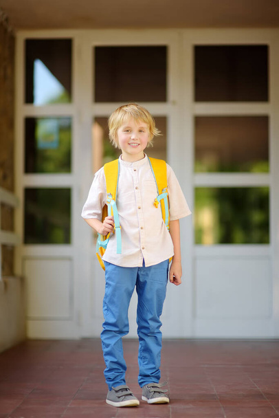 Little student with a backpack at the door of the stairs of school building. Kids back to school concept. - Photo, Image