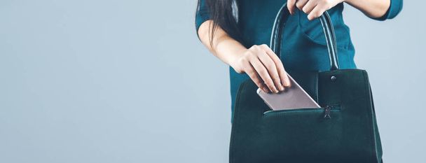 woman hand phone with bag on gray background - Zdjęcie, obraz