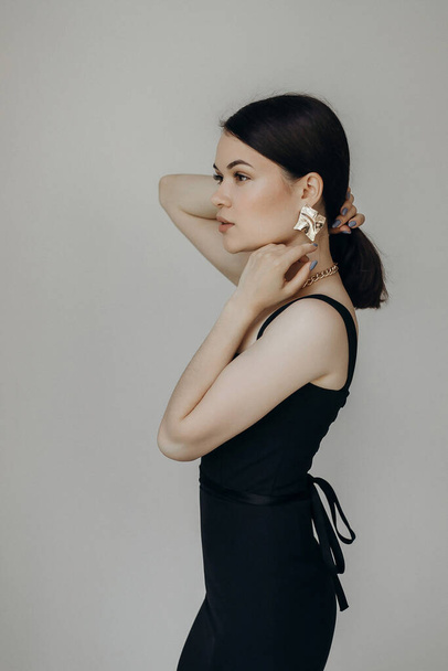 A girl in a black dress stands on a white background - Foto, afbeelding