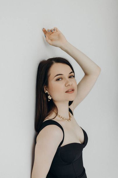 A girl in a black dress stands on a white background - Foto, afbeelding