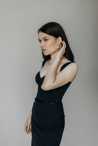 A girl in a black dress stands on a white background - Fotografie, Obrázek