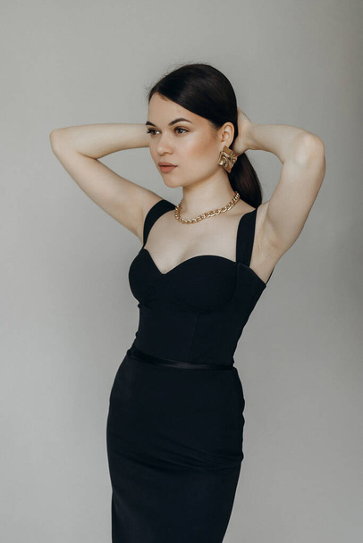 A girl in a black dress stands on a white background - Photo, Image