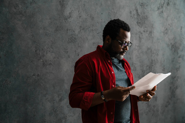 Black bearded man in eyeglasses working with papers indoors - Photo, Image