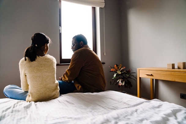 Black girl and her father talking while sitting on bed at home - Fotoğraf, Görsel