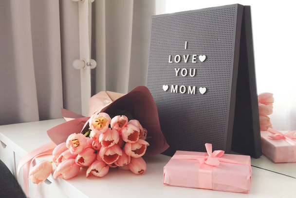 Beautiful tulips with the letter I LOVE MOM on letterboard sign. Pink background, frame, border. Lovely greeting card with tulips for Mothers day, wedding or happy event concepts. - Foto, Imagem