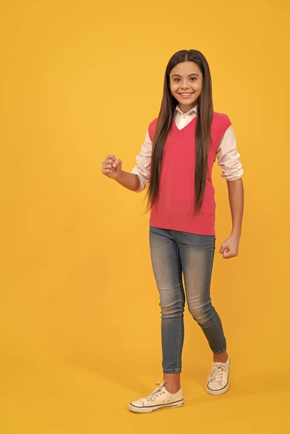happy teen school girl walking on yellow background, copy space, fashion. - Fotoğraf, Görsel