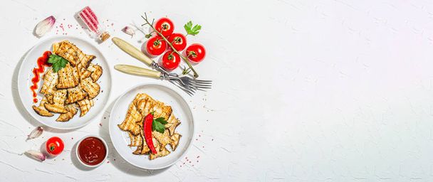 Fried slices Pleurotus eryngii mushrooms with sauce, spices and herbs. Healthy vegan food concept, hard light, dark shadowwhite plaster background, flat lay, banner format - 写真・画像