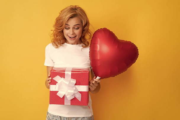 verbaasd roodharige meisje met liefde hart ballon en doos. ben mijn valentijn. - Foto, afbeelding