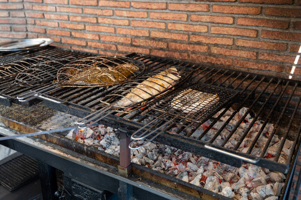 Grillades de poissons frais sur de vieux parrillas de charbon de bois de poisson blanc bar et turbot, construit à l'extérieur des bâtiments dans le petit village de pêcheurs Getaria, Pays basque, Espagne - Photo, image