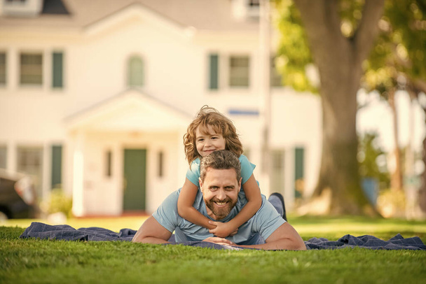 glücklicher Vater, der Spaß mit Kind hat, entspannen Sie sich gemeinsam auf grünem Parkrasen, Freunden. - Foto, Bild