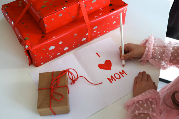 Happy Mother's Day! A little girl makes a postcard and gifts for mom. - Foto, afbeelding