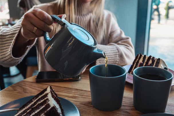 A girl in a cafe pours tea into cups. Beautiful cozy photo. - Foto, Bild
