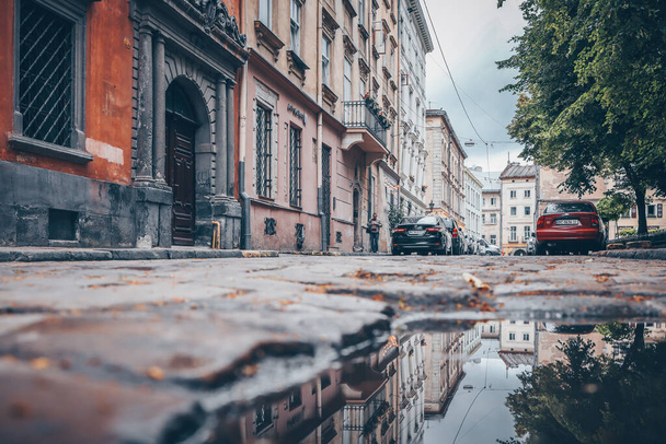 Rainy day in the big city, the cars drive along the old road. Close up view of a hatch at the level of the asphalt - Fotoğraf, Görsel