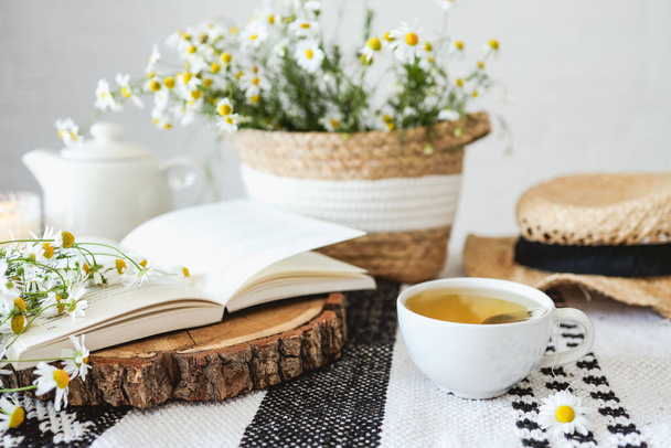 Open book, herbal chamomile tea cup on wooden table, reading and morning relax concept - Φωτογραφία, εικόνα