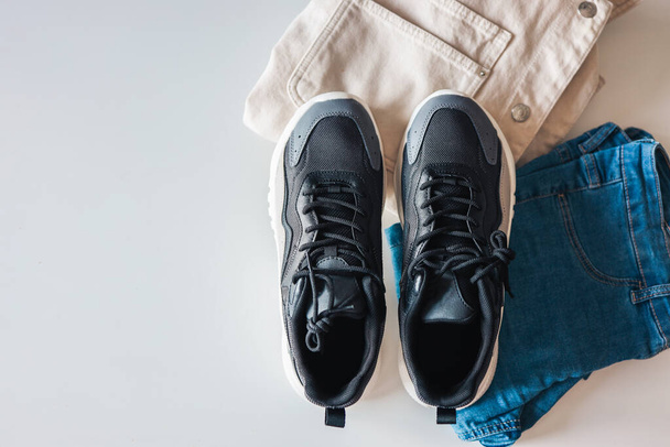 Stylish men's clothing flat lay. Black sneakers, jacket and jeans on a white background, top view. - Photo, image