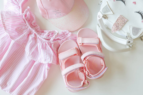 Set of clothes for a little girl, sandals, bag, cap, flat lay top view. - Photo, Image