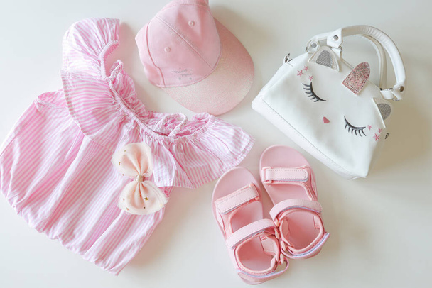 Set of clothes for a little girl, sandals, bag, cap, flat lay top view. - Фото, изображение