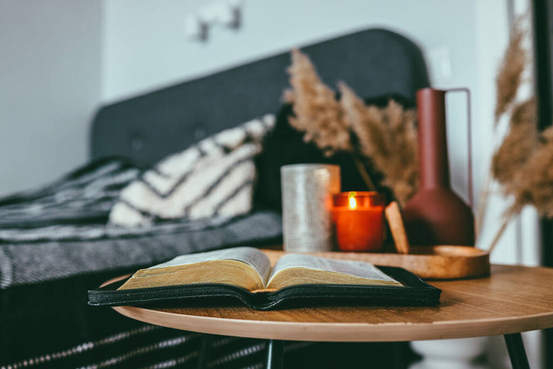 Open bible on wooden table in bedroom, scandinavian interior - Foto, Bild