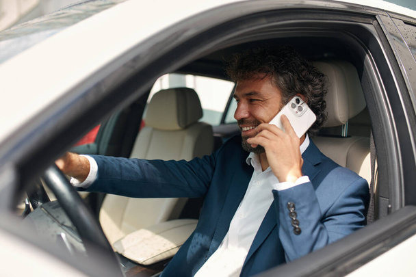 Closeup Caucasian Man Picking Up Phone at Car. Focused Positive Man Talking Smartphone at Automobile. Businessman Using Mobile Phone  - Φωτογραφία, εικόνα
