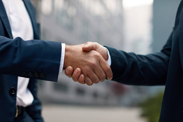 Two Businessmen Making Handshake Together. Colleagues Shaking Hands Outdoors in City Office Building Background. Agreement Concept - Foto, Imagem