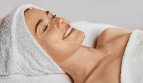 Portrait woman lying on a lounger in a spa salon waiting for therapy to begin. Beauty woman face skin care. Health care, beauty treatment. Smiling girl. - Foto, Bild