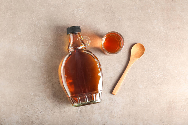 Bottle and glass of maple syrup on light background - Foto, imagen